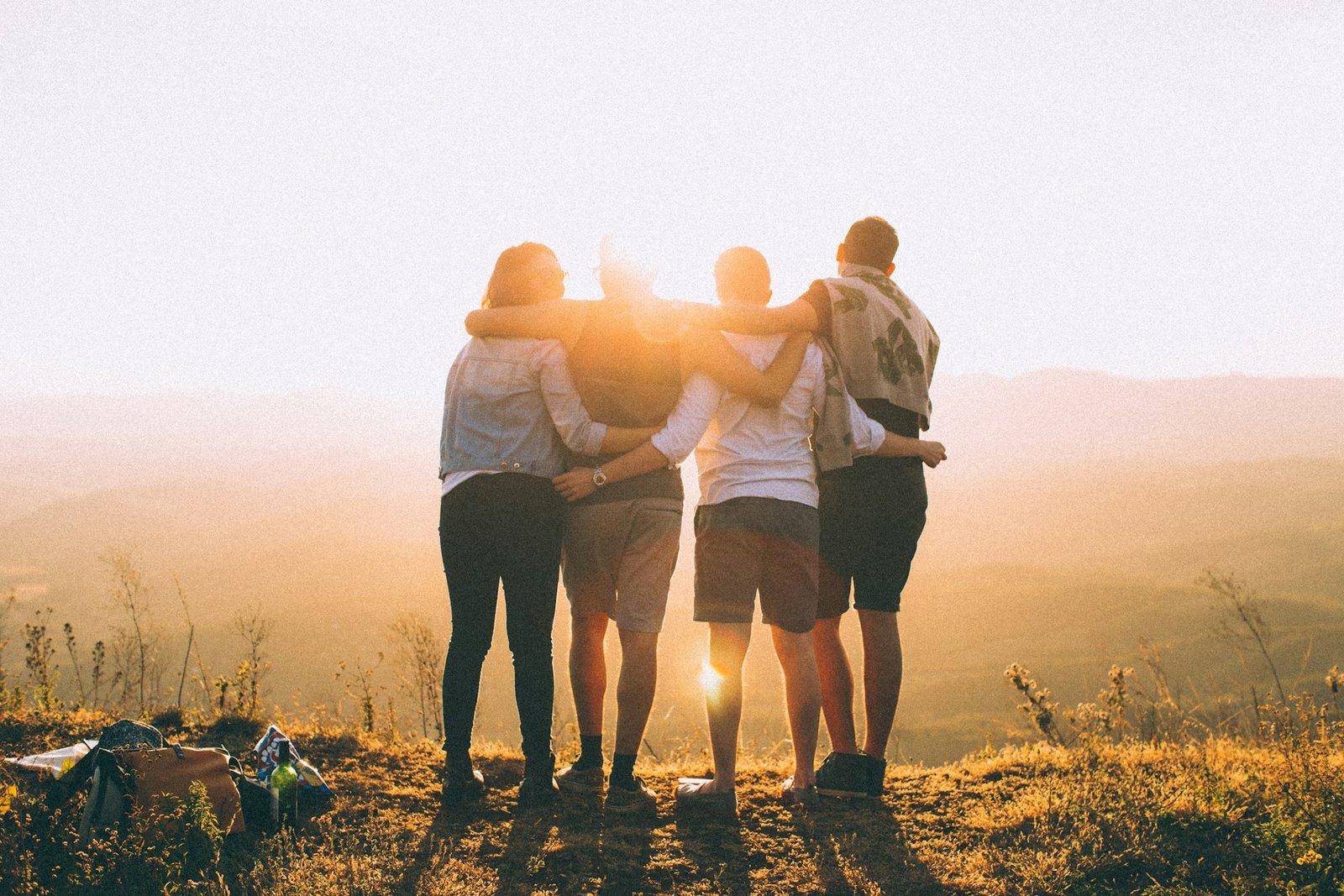 Grupo de personas abrazadas mirando el atardecer, apoyo familiar y social
